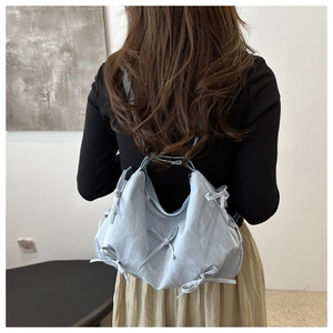 Detail of light blue pleated tote bag with decorative string bows and silver zipper