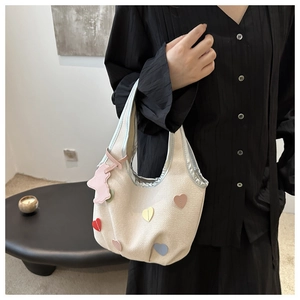 Détail du sac fourre-tout en toile crème avec patchs cœurs colorés et breloque lapin