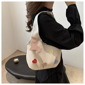Détail du sac beige avec patchs cœurs colorés et un charmant pendentif mouton rose