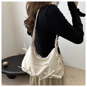 Detail view of cream white pleated tote bag with handcrafted decorative bows on model