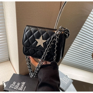 Détail d'un sac bandoulière noir matelassé avec une étoile argentée et une bandoulière chaîne