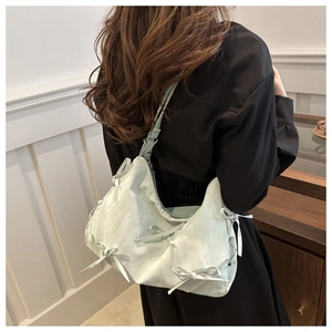 Detail view of mint green pleated crossbody bag with decorative bow ties and zipper