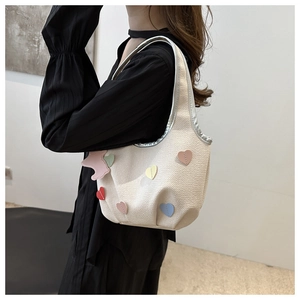 Détail du sac hobo crème avec patchs cœurs colorés et bordures métalliques argentées