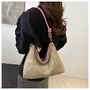 Macro detail of hand-woven straw bag featuring a vibrant pink strap and delicate lace bow