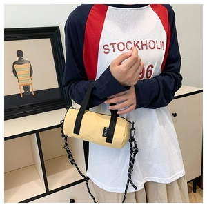 Détail du sac cylindrique jaune avec poignées noires et bandoulière rayée