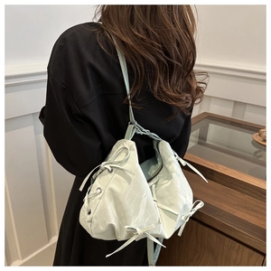 Detail view of stylish mint green tote bag featuring decorative bows and faux leather texture