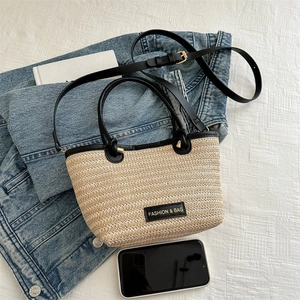 Détail du sac cabas en paille tissée avec bordure en cuir noir et bandoulière réglable