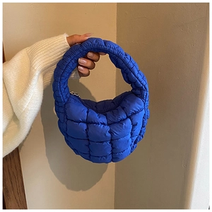 Detail of blue quilted cloud bag showing soft padded nylon texture and crescent shape