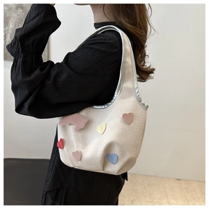 Gros plan du sac hobo en tricot blanc avec patchs cœurs colorés et applique animal rose