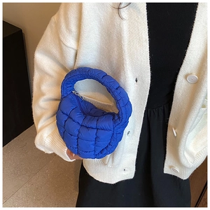 Detail of royal blue quilted cloud bag held by model with minimalist fashion aesthetic