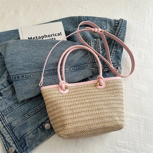 Détail du sac cabas en paille avec bordure en cuir rose et boucles métalliques