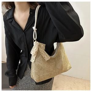 Detail of summer straw hobo bag with lace bow and woven rope strap on model