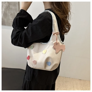 Détail du sac blanc texturé avec patchs en forme de cœur et breloque petit chien
