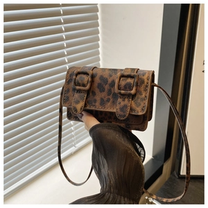 Vue détaillée du mini sac bandoulière léopard avec doubles boucles tenu à la main