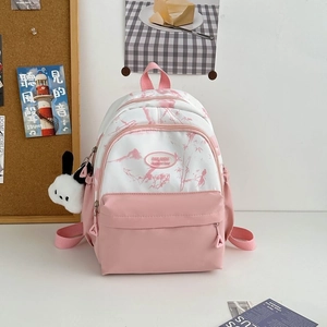 Detail view of a pink and white nylon backpack with floral patterns and a cute plush charm