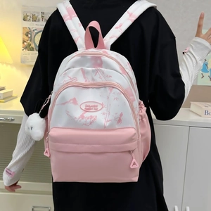 Detail of pink tie-dye nylon backpack with plush bunny charm and zip pockets