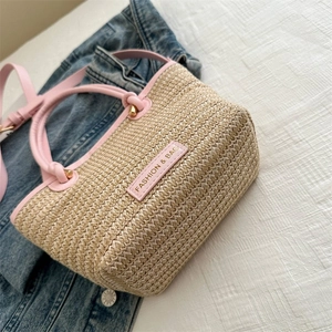 Détail d'un sac cabas en paille tissée avec garniture et poignées en cuir rose sur denim