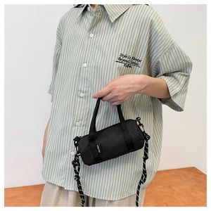Détail d'un sac à bandoulière noir cylindrique avec sangle tissée sur un modèle