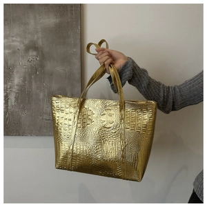 Detail of gold faux-crocodile embossed texture on a large capacity tote shoulder bag