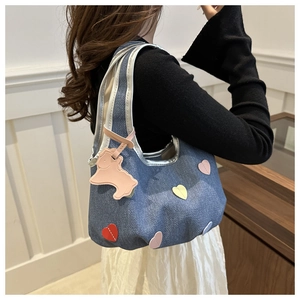 Sac hobo en denim bleu avec patchs cœurs colorés et breloque chiot rose porté