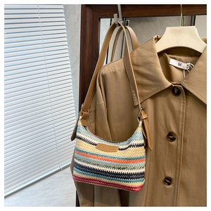Close-up of rainbow woven straw handbag featuring colorful stripes and leather handle