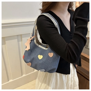 Détail du sac à bandoulière en denim avec appliqués de cœur et charme d'ours