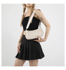 Dettaglio della borsa a spalla intrecciata beige con borchie argentate sulla tracolla