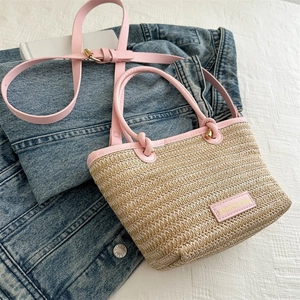 Détail d'un sac à main en paille tressée avec bordure en cuir rose sur un jean bleu