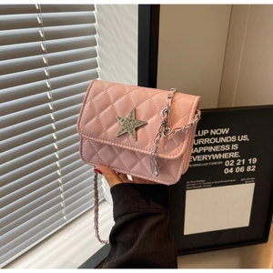 Gros plan du sac bandoulière matelassé rose avec étoile argentée et bandoulière chaîne