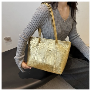 Detail of gold oversized tote bag with crocodile pattern texture and metallic finish