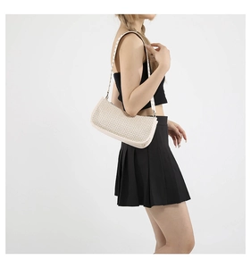 Dettaglio di una borsa a spalla in paglia intrecciata color crema con trama fine