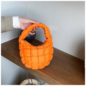 Detailed view of the bright orange quilted cloud bag with a soft puffy texture