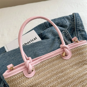 Détail du sac cabas en paille tressée avec anse en cuir rose et finitions dorées