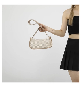 Dettaglio di una borsa a spalla in tessuto beige con finiture marroni e borchie metalliche