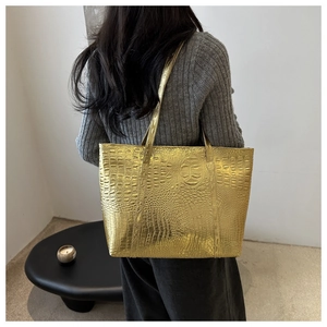 Golden crocodile embossed tote bag with metallic finish shown from a side view on model