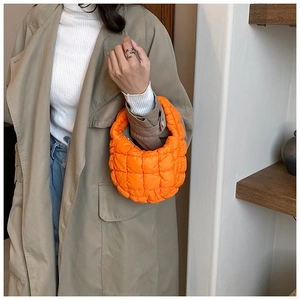 Detail of bright orange quilted puffer handbag with a soft padded texture for women