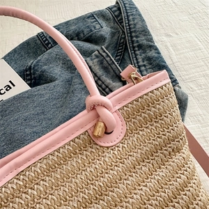 Détail du sac cabas en paille tressée avec poignée en cuir rose et métal doré