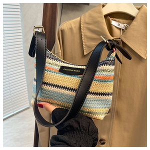 Close-up of rainbow woven straw crescent bag with adjustable black leather strap