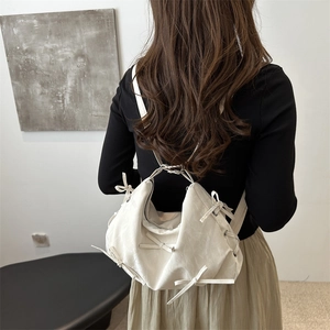 Versatile cream PU leather tote bag with bow details worn as a stylish backpack