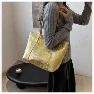 Detail of golden crocodile pattern tote bag with high-end metallic texture and slim straps