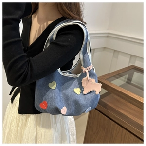 Détail du sac hobo en jean bleu avec patchs cœurs colorés et breloque cheval rose