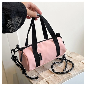 Détail d'un sac cylindrique en nylon rose avec bandoulière tressée et étiquette tissée