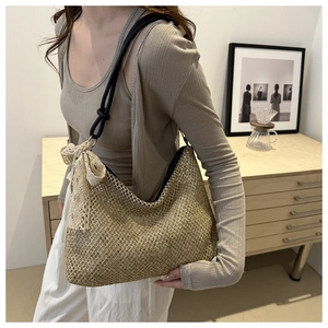 Close-up of woven straw tote bag with delicate lace bow and black rope shoulder straps