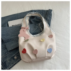 Détail du sac cabas en tissu crème avec écussons cœurs colorés et poignées métallisées