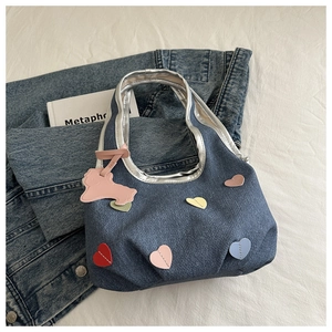 Sac à main en denim avec patchs en cœur et charm chiot rose sur fond blanc texturé