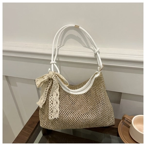 Detail of woven straw shoulder bag with white leather strap and lace ribbon bow decoration