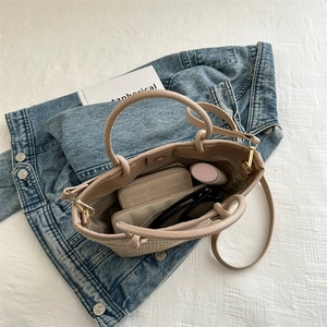 Vue intérieure du sac cabas tissé beige avec cosmétiques, portefeuille et lunettes de soleil