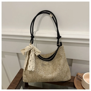 Detail of woven straw bag featuring black leather trim and elegant white lace bow