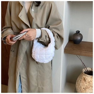 Minimalist white quilted cloud bag shown in a lifestyle setting on a wooden shelf