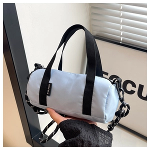 Détail du sac baril en nylon bleu clair avec étiquette tissée et bandoulière en corde à motifs